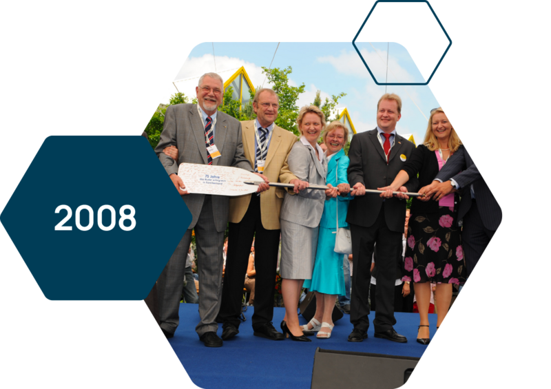 The Heinrichs family holds a paddle with the inscription "75 years – Successfully Steering the Family Business."