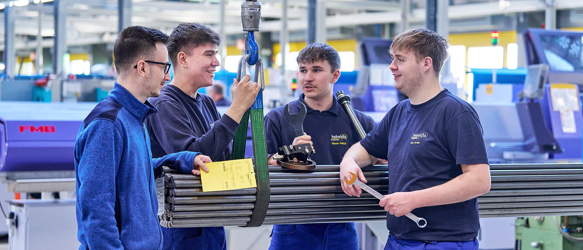 Vier Azubis von heinrichs drehteile stehen an Stahlrohren