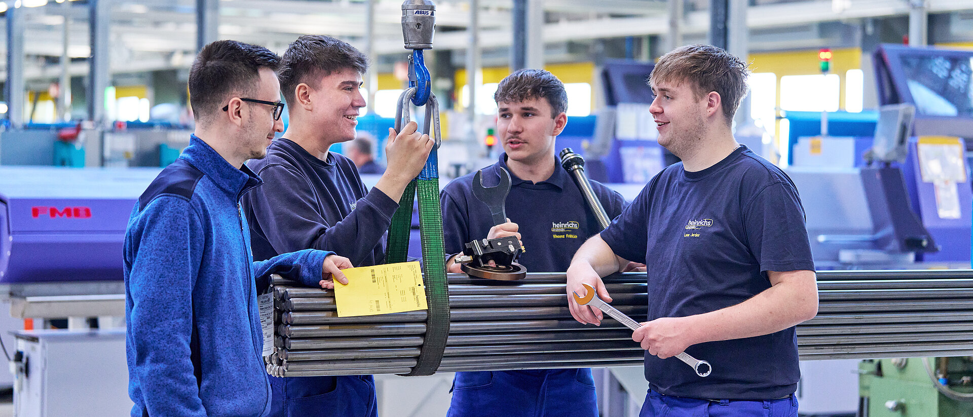 Vier Azubis von heinrichs drehteile stehen an Stahlrohren