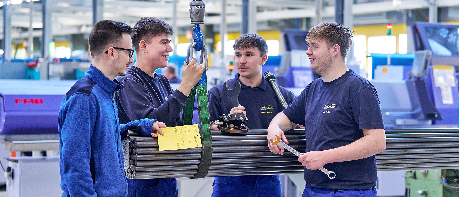 Vier Azubis von heinrichs drehteile stehen an Stahlrohren