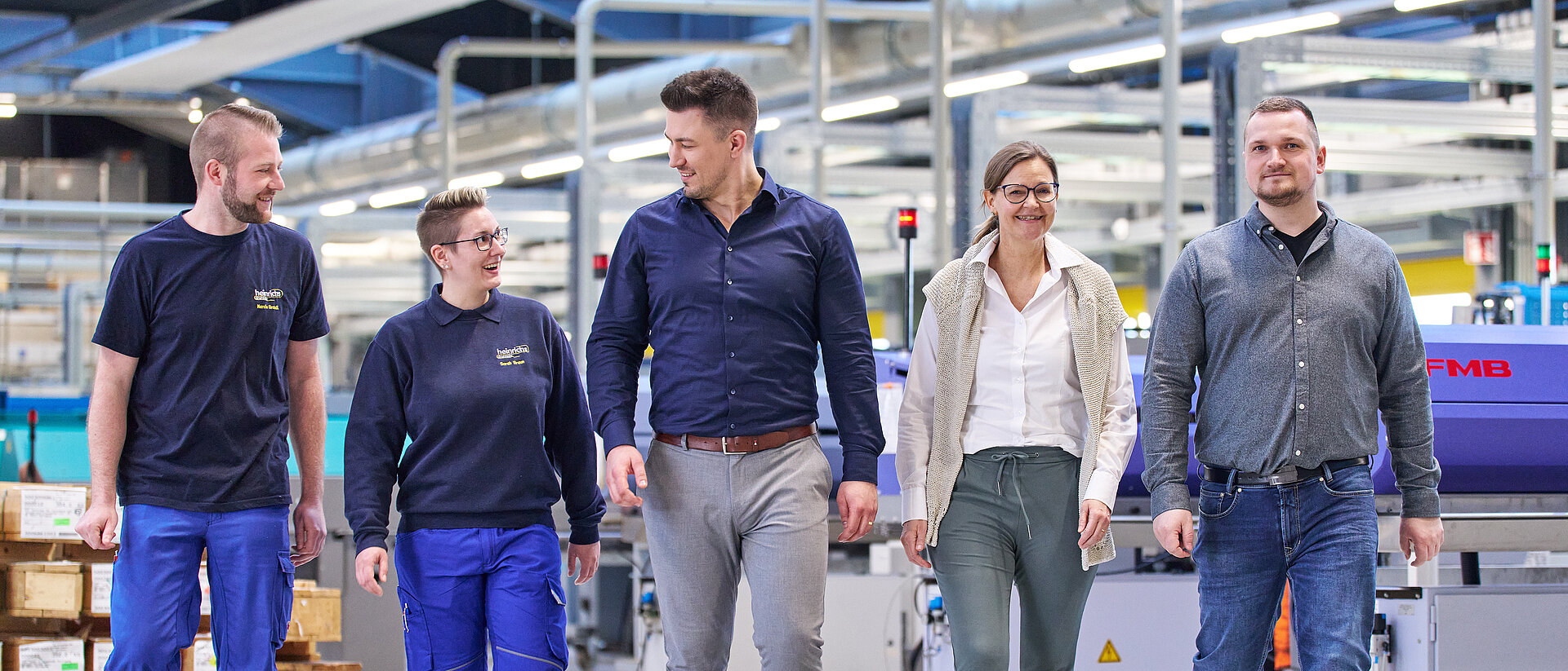 Gemischtes Team in der Werkhalle von heinrichs