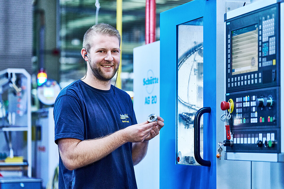 Mitarbeiter steht vor Produktionsmaschine